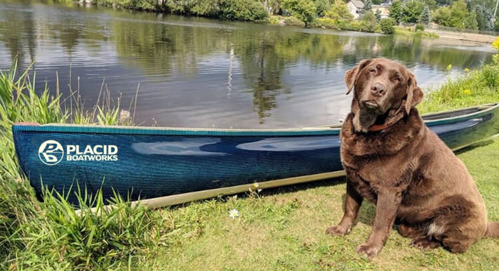 dog sitting next to Placid Boatworks lightweight pack canoe