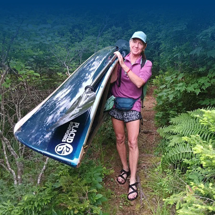Woman Carrying Placid Boatworks Pack Canoe Through Woods